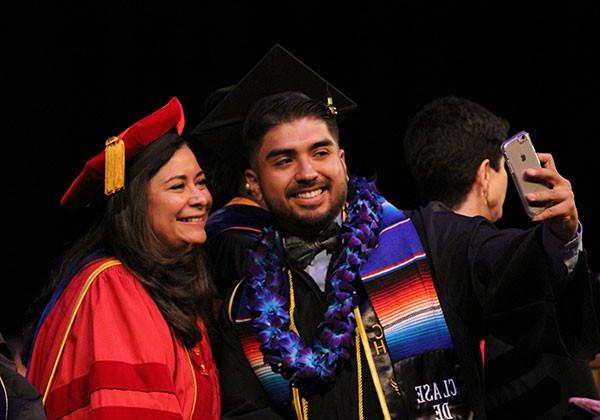 A graduate takes a selfie with a professor